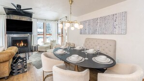 Un comedor moderno con una mesa redonda para seis, una chimenea y un cuadro abstracto grande en la pared.