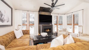Una sala de estar moderna con chimenea, ventanas amplias y un ventilador de techo.