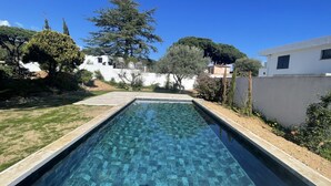 A rectangular swimming pool with a clear blue water surface, surrounded by a grassy area and various trees. - Le Jasmin by Interhome (Cavalaire)
