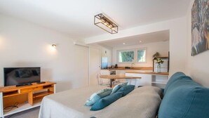A modern bedroom with a bed, a TV, a desk, and a kitchenette. - Le Jasmin by Interhome (Cavalaire)