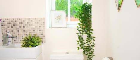 Un baño con inodoro, lavamanos y ventana con vista a la vegetación.