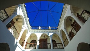 A courtyard with a blue sky visible through the ceiling, white walls, and arches. - Villa Agora (Sidi Abdallah Ghiat)