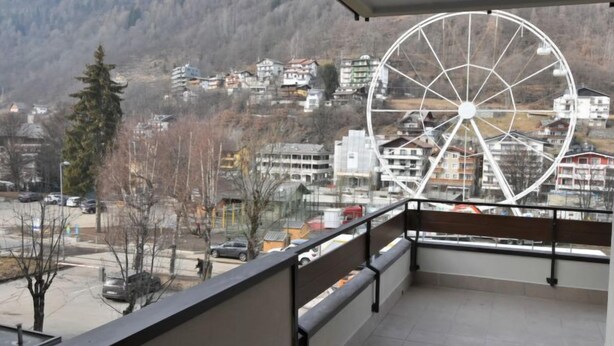 A balcony with a view of a town and a large Ferris wheel. - Stefania by Interhome (Aprica)