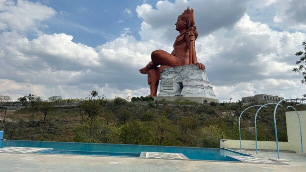 A large statue on a pedestal with a pool in the foreground. - Shiv Ashray Resort (Nathdwara)