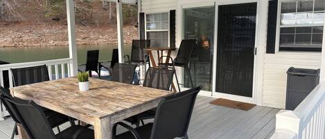A covered deck with a table and chairs, a ceiling fan, and a view of a body of water.