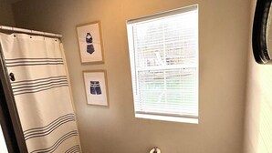 A bathroom with a toilet, a sink, a shower curtain, and a window with blinds. - Floating Cabin - Another Day in Paradise at Whitman Hollow Marina (LaFollette)