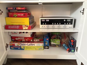 A cabinet with various board games and a Bluetooth speaker.