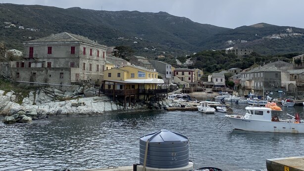 A coastal village with traditional buildings, a harbor with boats, and a mountainous backdrop. - Holiday residences 5 minutes from the beach (Centuri)