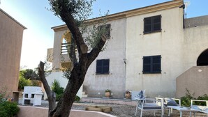 A building with a beige facade, black shutters, and a tree in the foreground. - Holiday residences 5 minutes from the beach (Centuri)