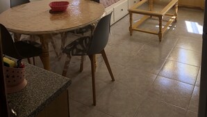 A compact room with a bed, a dining table with chairs, a small table, a mirror, and a window with curtains. - Holiday residences 5 minutes from the beach (Centuri)
