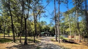 Un terrain de camping doté d’un espace pique-nique couvert, d’un sentier de gravier et d’une remorque.