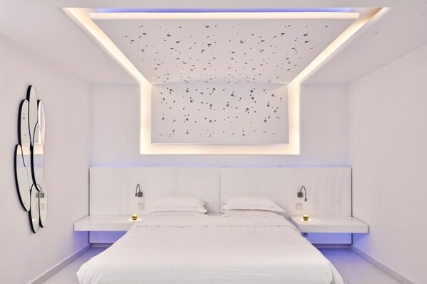 Une chambre moderne avec un grand lit, des tables de chevet et un design de plafond original.