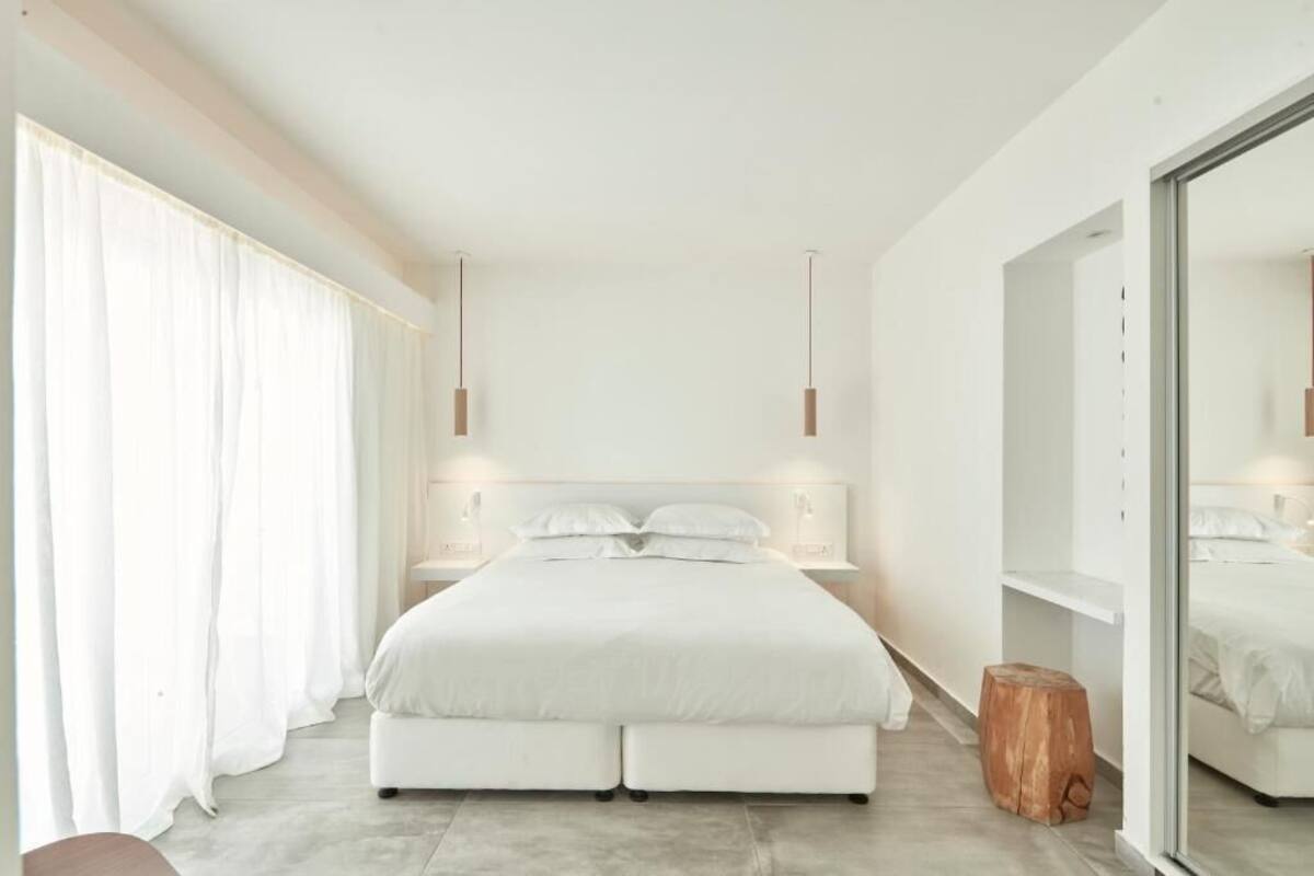 A modern bedroom with a large bed, bedside tables, and a mirror.