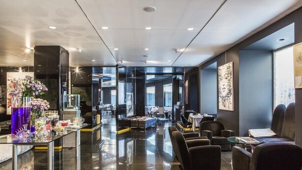 A modern hotel lobby with a glass coffee table, seating area, and artwork on the walls. - Autograph Collection Palazzo Matteotti, The Dedica Anthology (Milan)
