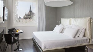 A hotel room with a large bed, a desk with a chair, a window with a view of a building, and a modern design. - Autograph Collection Palazzo Matteotti, The Dedica Anthology (Milan)