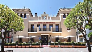 A hotel with a central entrance, outdoor seating, and a clock on the facade. - Hotel Casa Consistorial (Fuengirola)