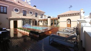 A rooftop pool area with a wooden deck, lounge chairs, and a swimming pool. - Hotel Casa Consistorial (Fuengirola)