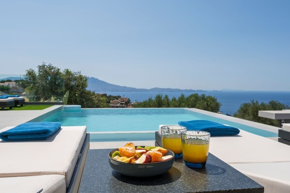 Una piscina al aire libre, sombrillas, sillones reclinables de piscina