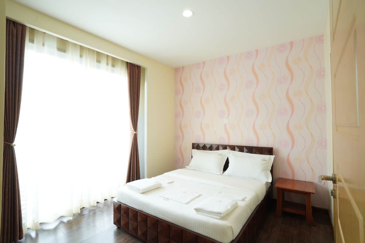 A neatly made bed with white linens, a wooden headboard, and a bedside table with a lamp.