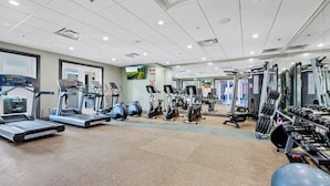 Un'ampia palestra con tapis roulant, ellittiche e attrezzature per sollevamento pesi.