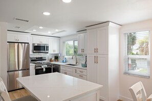Une cuisine moderne avec des meubles blancs, des appareils en acier inoxydable et un îlot central.