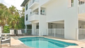 A swimming pool with a white building in the background. - Hidden Pearl 2 Bedroom Home by RedAwning (Holmes Beach)