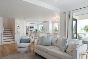 Una sala de estar moderna con un sofá, una silla y un comedor con una mesa y sillas.