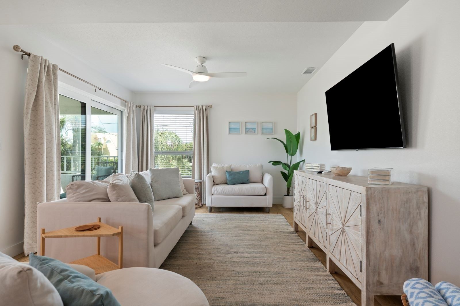 Un salon moderne avec un canapé, un fauteuil et un téléviseur fixé au mur.