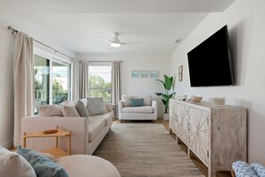 A modern living room with a sofa, armchair, and a TV mounted on the wall.