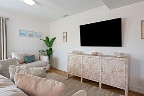 Een woonkamer met een bank, een plant, een kast en een televisie.