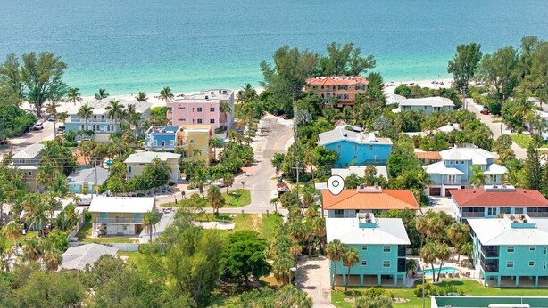 A coastal residential area with houses, a beach, and a clear view of the ocean. - Hidden Pearl 2 Bedroom Home by RedAwning (Holmes Beach)