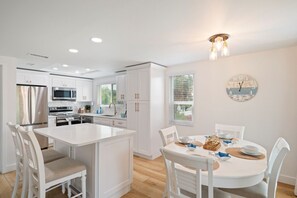 A modern kitchen with white cabinetry, stainless steel appliances, and a central island with seating.