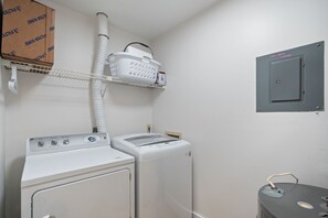 A laundry room with a washing machine, dryer, and a shelf with a basket.