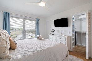 Een slaapkamer met een bed, een dressoir, een televisie en een inloopkast.
