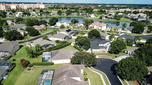 Vue aérienne d’un quartier résidentiel avec des maisons, un lac et un terrain de golf.