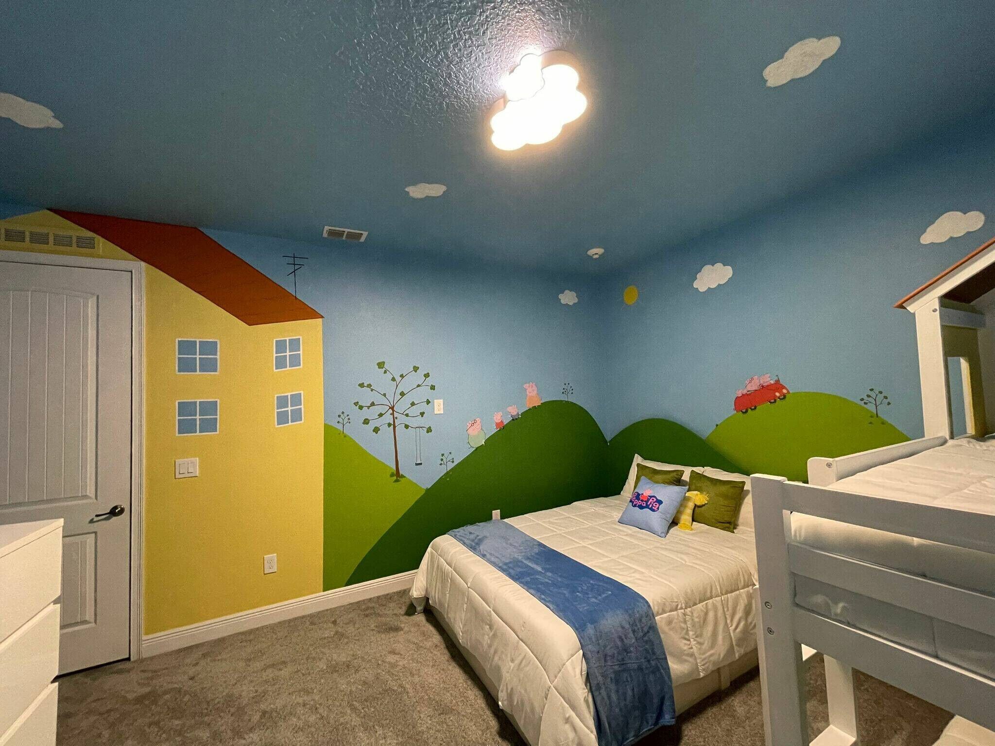 Une chambre à coucher avec un lit, une commode et une table de chevet. Il y a une fenêtre qui donne sur une maison et des collines.