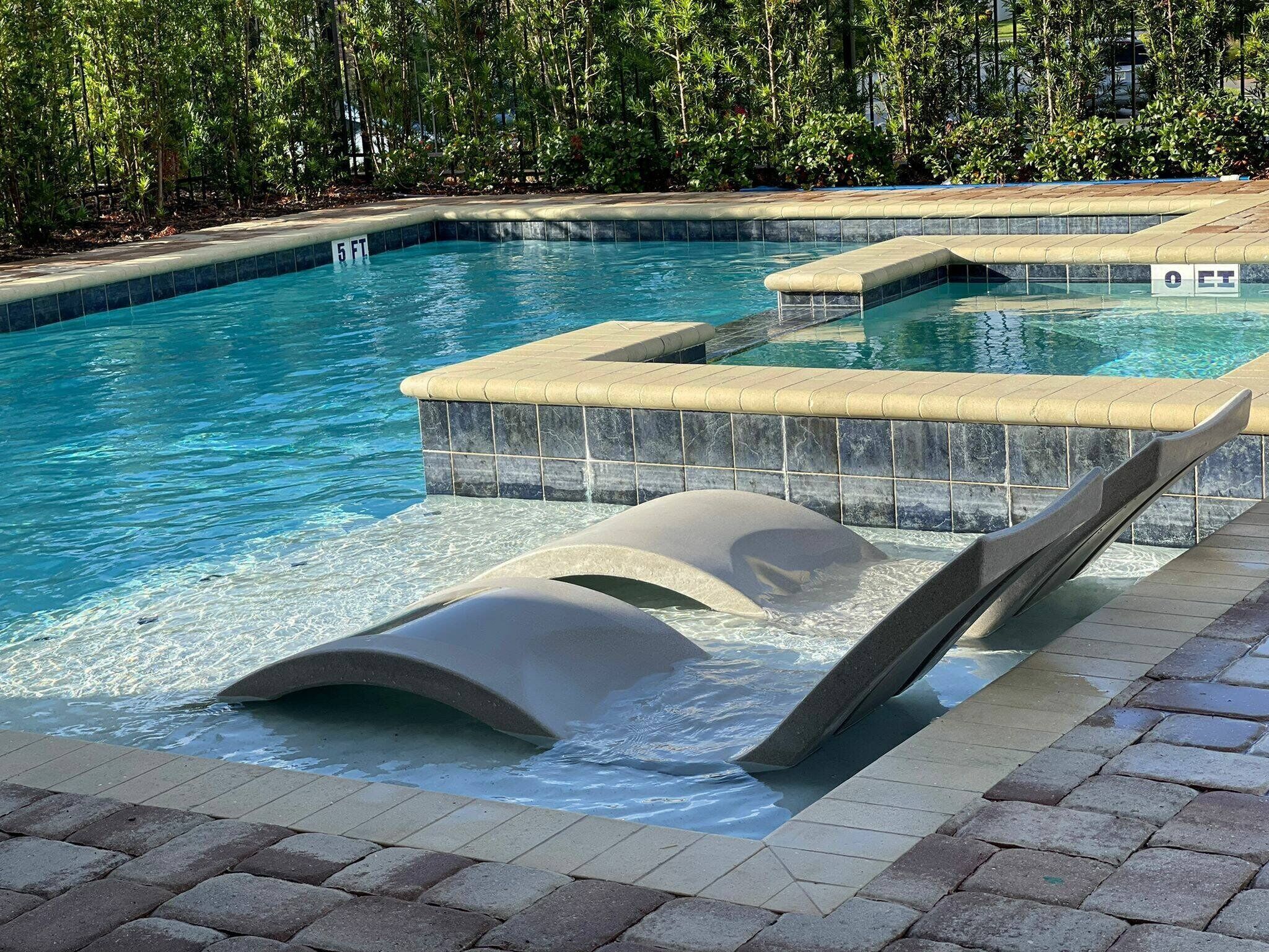 Ein Schwimmbecken mit Wasserrutsche und gefliestem Beckenrand.