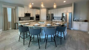 A modern kitchen with a large island, stainless steel appliances, and pendant lighting. - Last Minute Disney! Private Pool, Hot Tub, Game Room & Themed Bedrooms. Book Now! #60031 (Orlando)