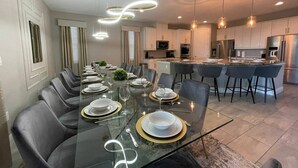 A modern kitchen with stainless steel appliances, a dining area with a glass table, and a bar with stools. - Last Minute Disney! Private Pool, Hot Tub, Game Room & Themed Bedrooms. Book Now! #60031 (Orlando)