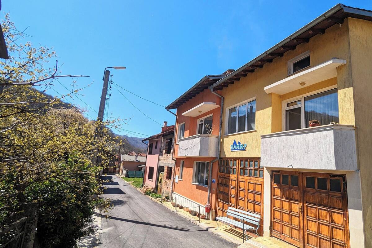 A row of residential buildings with a garage door, a bench, and a clear sky.