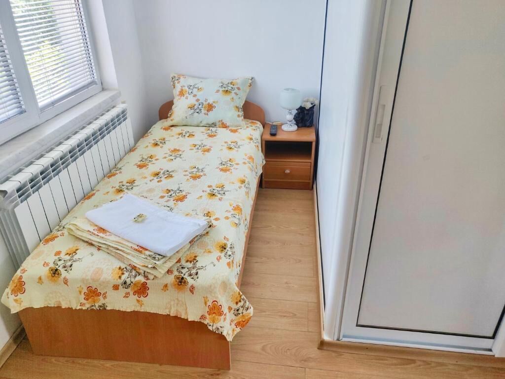 A small bedroom with a single bed, a bedside table, a lamp, and a radiator.