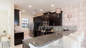 Una cocina moderna con armarios oscuros, encimeras de granito, electrodomésticos de acero inoxidable y una isla integrada con asientos.