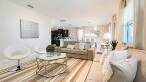 Una sala de estar moderna con un sofá, sillones y una mesa de centro de vidrio.