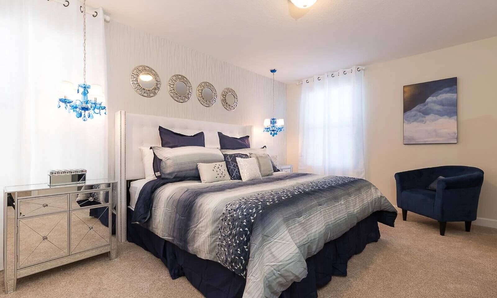 A bedroom with a large bed, a dresser, a chair, and a painting on the wall.