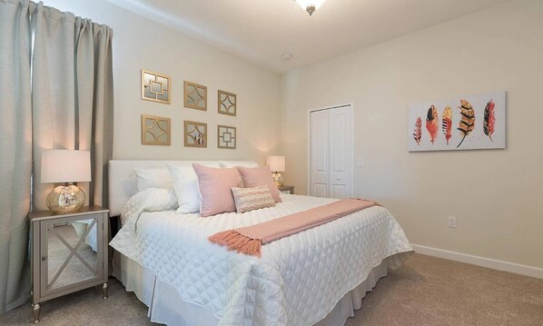 A bedroom with a bed, bedside tables, a door, and wall art.