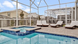 Un área de piscina con cerramiento de vidrio, sillas de descanso y una piscina con azulejos.