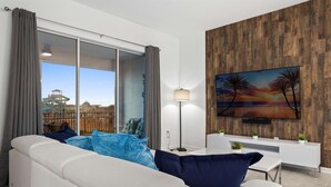 Un salon moderne avec un canapé blanc, une table basse et un téléviseur fixé à un mur en bois.