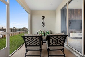 Enjoy the serene view of the lush lawn from the balcony, featuring two comfortable chairs and a decorative art piece.