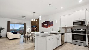 Une cuisine moderne avec des meubles blancs, des appareils en acier inoxydable et un grand îlot central.