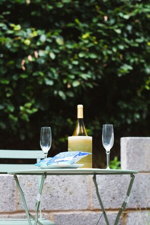 Ein Tisch mit einer Flasche und zwei Gläsern, vor einer grünen Kulisse.